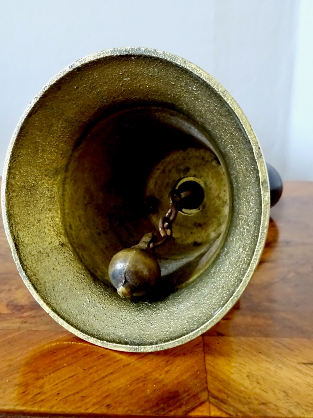 A cast brass hand bell featuring a turned dark wood handle and stamped military markings dated 1942. View IX