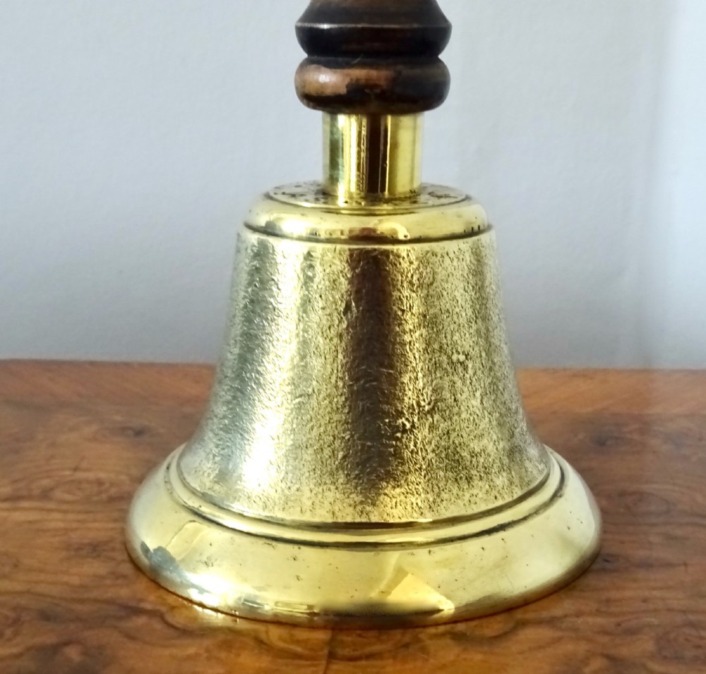 A cast brass hand bell featuring a turned dark wood handle and stamped military markings dated 1942. View XI