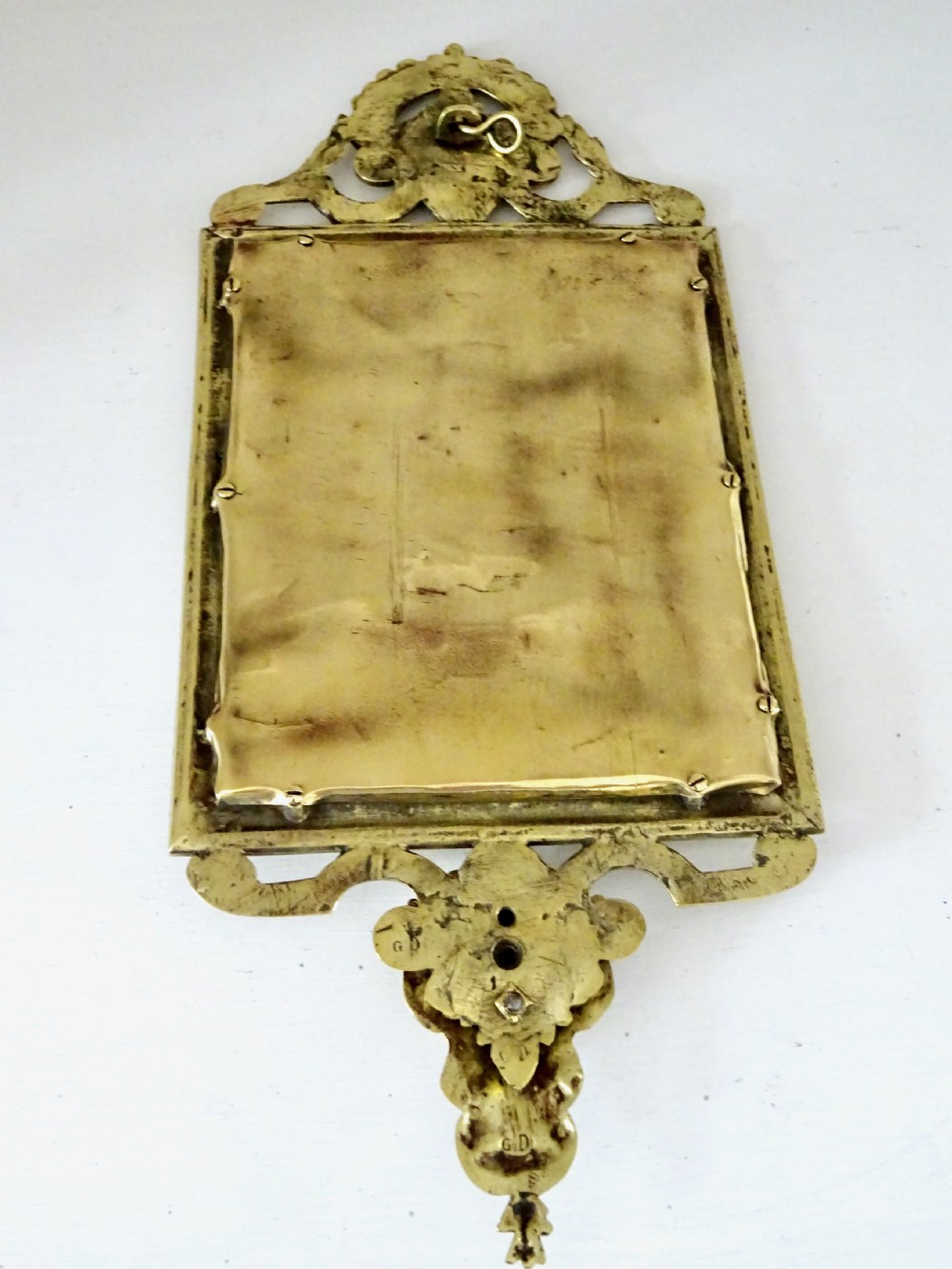 An ornate rectangular cast bronze wall mirror featuring a bevelled glass plate, classical scroll cresting, embossed repeating frame pattern, and a mask apron at the bottom. View VI