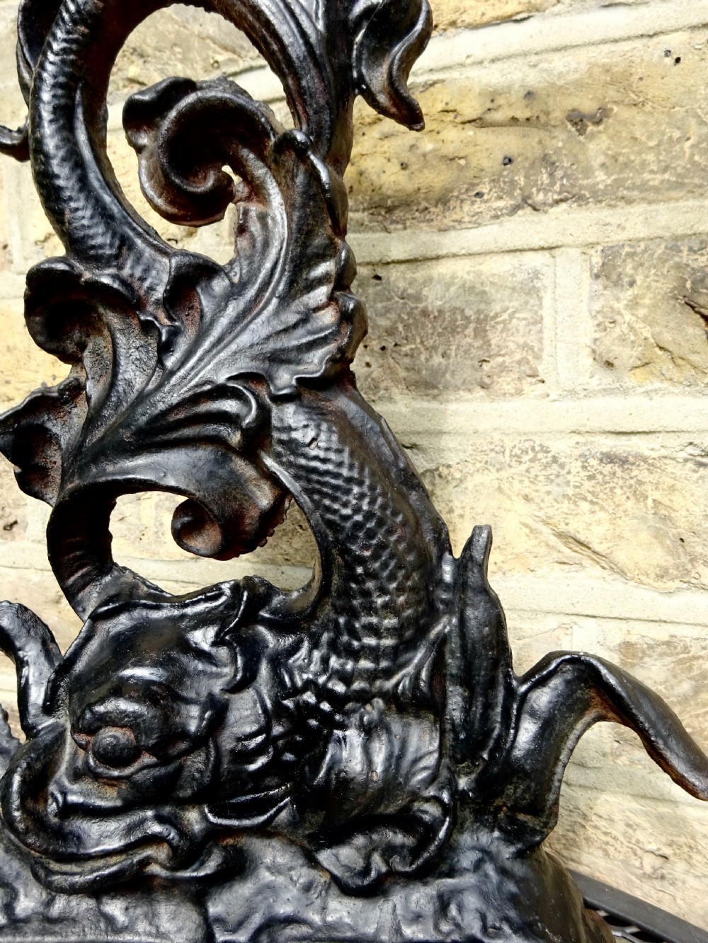 A heavy black cast iron doorstop featuring a mythological dolphin intertwined with acanthus scrollwork set upon a rectangular molded base. View V