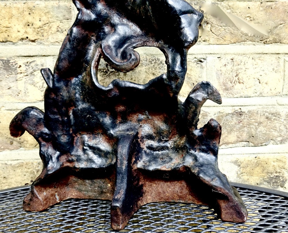 A heavy black cast iron doorstop featuring a mythological dolphin intertwined with acanthus scrollwork set upon a rectangular molded base. View VII