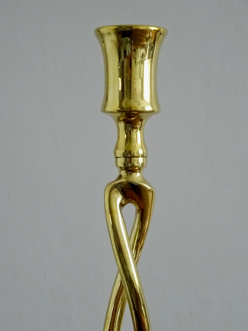 A pair of polished gold brass candlesticks featuring open-twist stems resting on circular bases. View IX