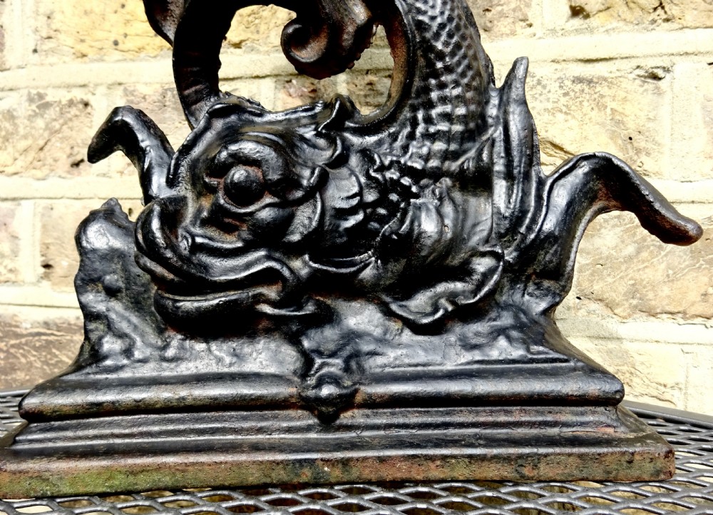 A heavy black cast iron doorstop featuring a mythological dolphin intertwined with acanthus scrollwork set upon a rectangular molded base. View IV