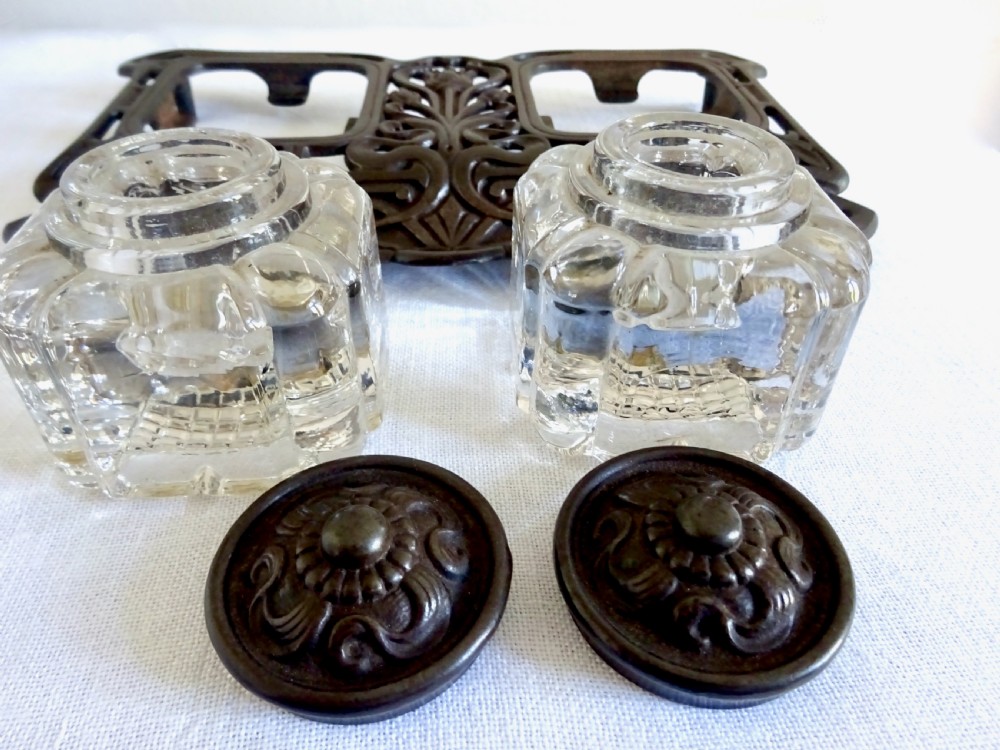 An Art Nouveau dark metal double inkstand featuring pierced floral scrollwork and two square glass inkwells with embossed metal lids. View IV