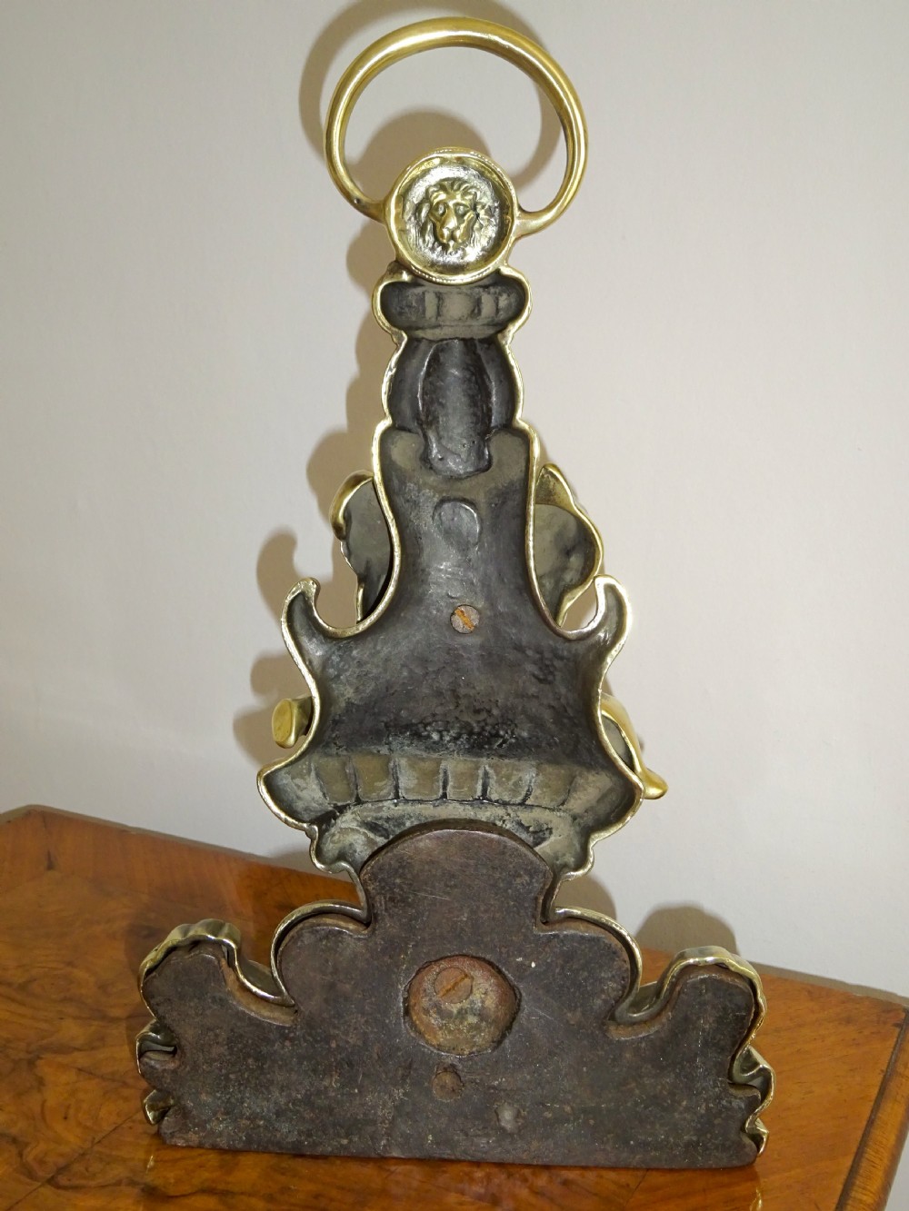 A late 19th-century cast brass doorstop featuring cherub figures, dolphin motifs, a lion mask, and a top ring handle. View VIII