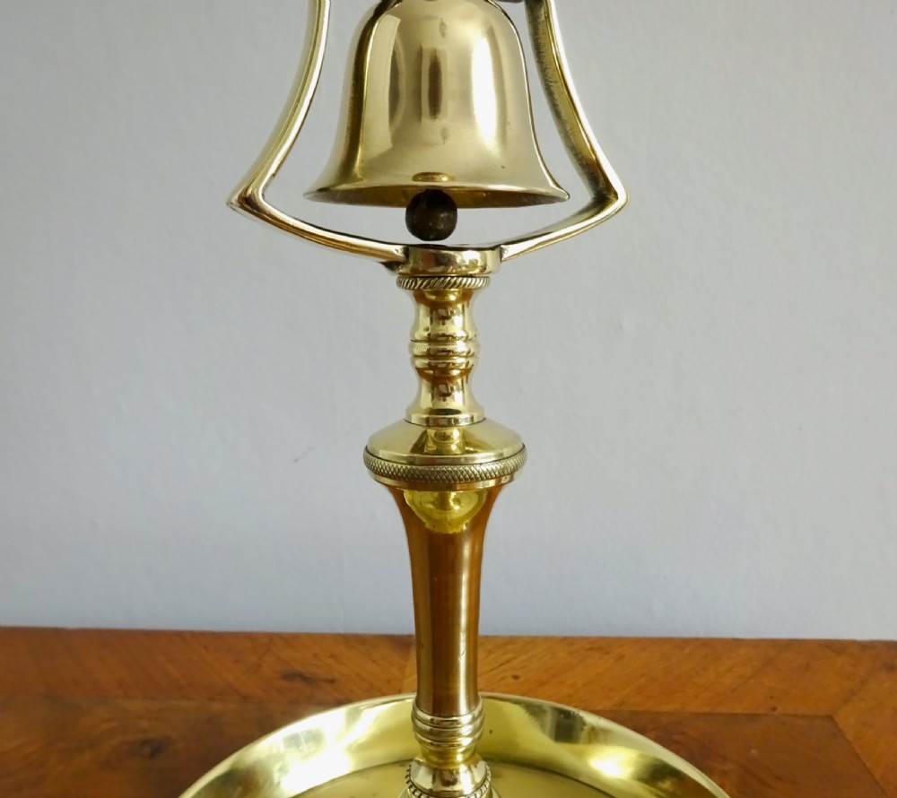 A pair of polished brass Victorian tavern candlesticks featuring turned stems, hanging bells suspended in frames, and wide saucer bases. View III
