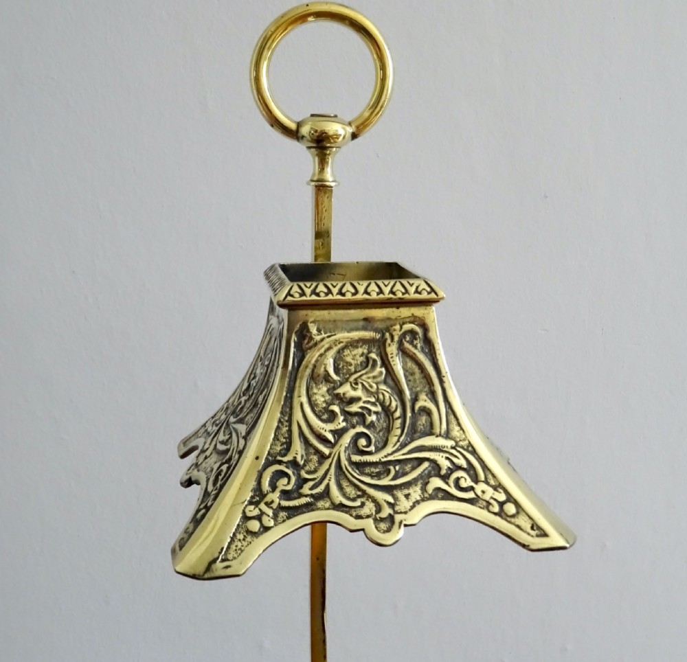 A late Victorian brass candle holder featuring a square cast tray base, a central candle socket, a tall stem, an adjustable metal shade decorated with relief scrollwork, and a top carrying ring handle. View III