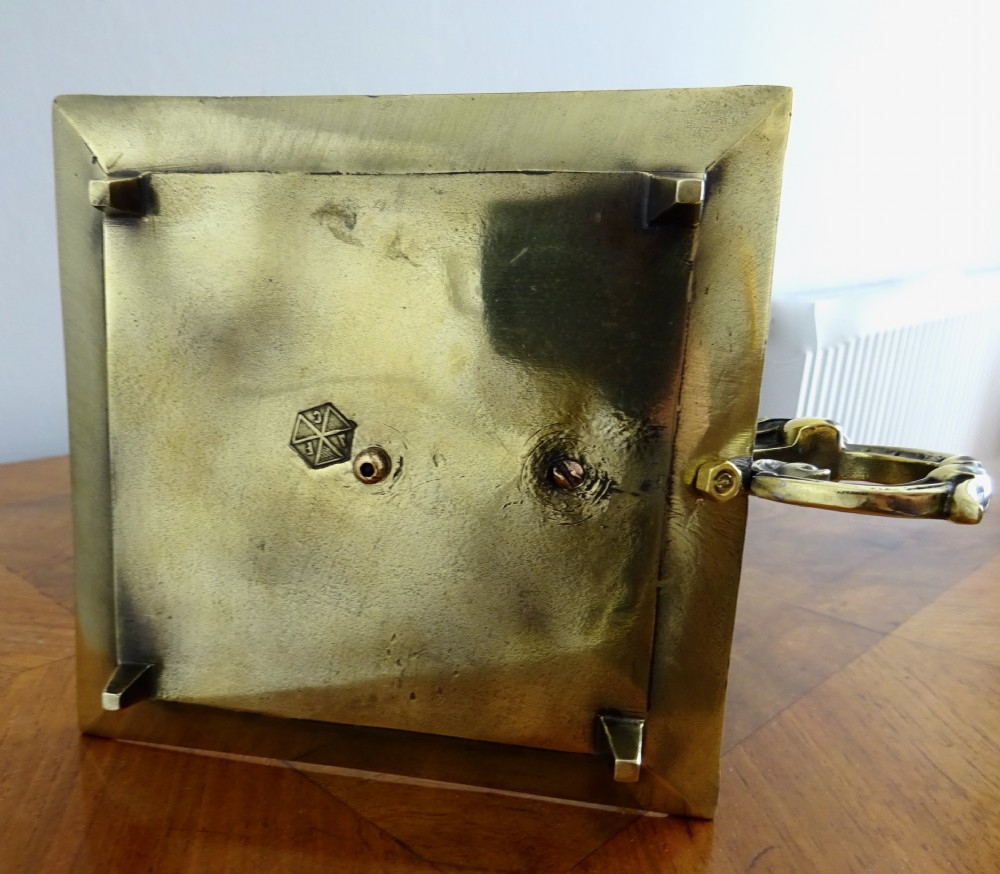 A late Victorian brass candle holder featuring a square cast tray base, a central candle socket, a tall stem, an adjustable metal shade decorated with relief scrollwork, and a top carrying ring handle. View IX