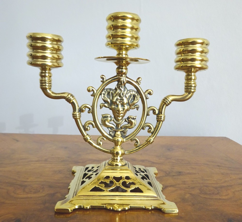 A pair of cast brass three-light candelabras featuring central grotesque mask motifs and pierced square bases. View III