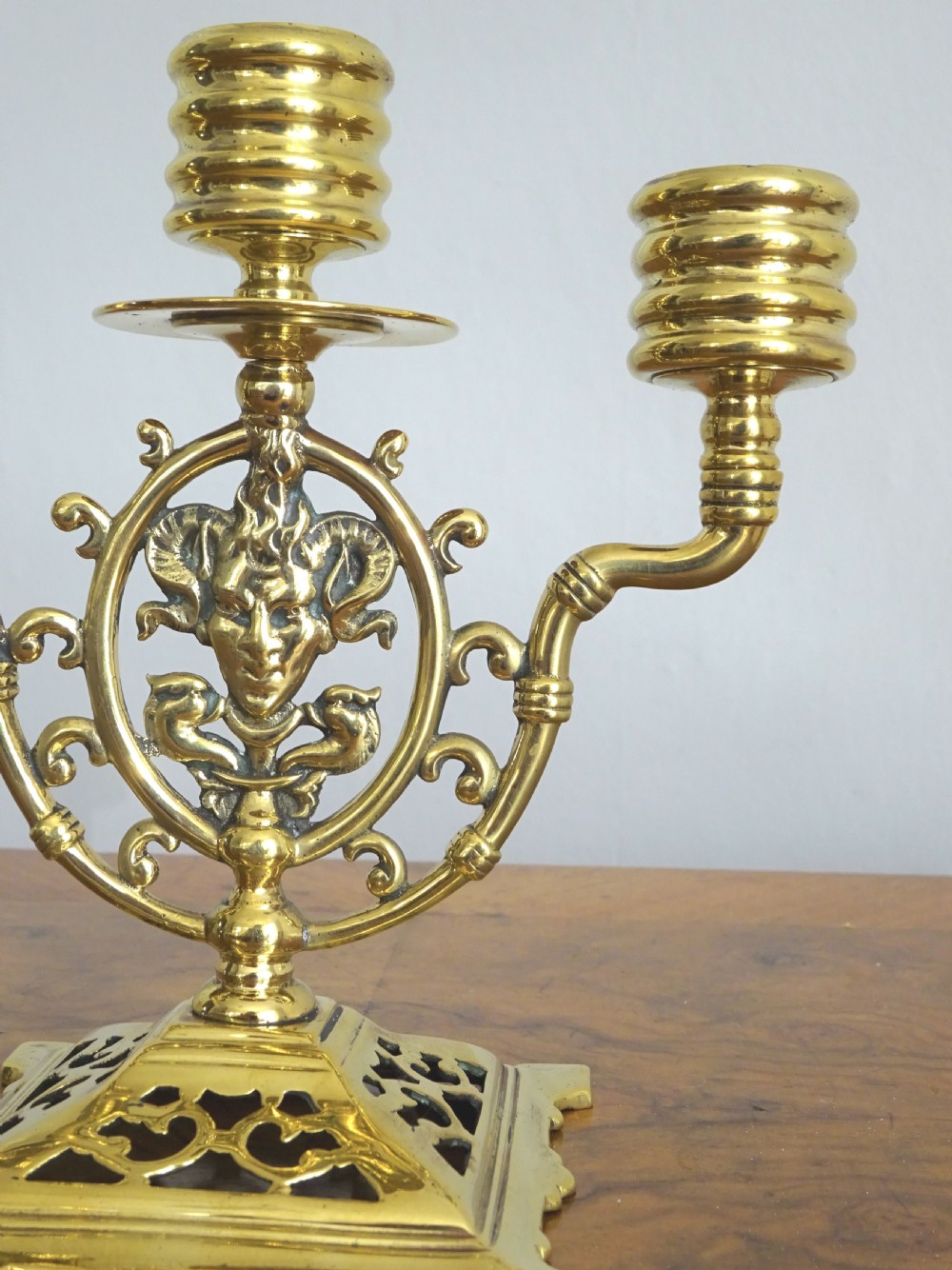 A pair of cast brass three-light candelabras featuring central grotesque mask motifs and pierced square bases. View VIII