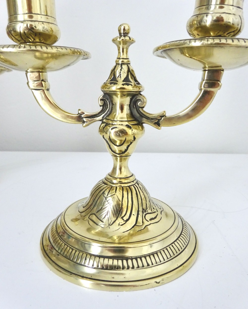 A pair of polished brass double-arm candlesticks featuring scrolled branches and gadrooned circular bases. View IV