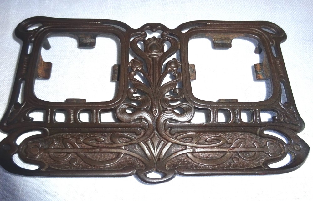 An Art Nouveau dark metal double inkstand featuring pierced floral scrollwork and two square glass inkwells with embossed metal lids. View II