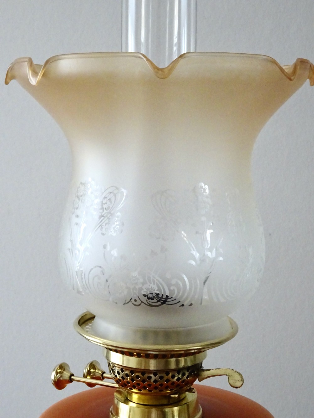 An antique oil lamp featuring a brass pedestal base, a hand-painted floral glass font, and a flared ruffled glass shade. View V