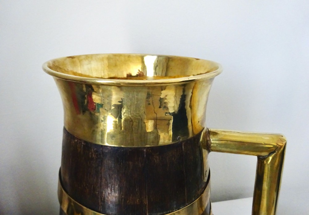 A Victorian coopered oak jug constructed from dark wooden staves with polished brass binding bands, rim, and handle. View IV