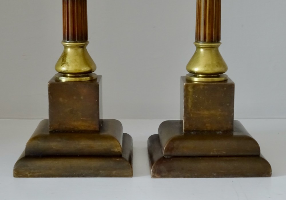 A pair of Edwardian bronze and brass candlesticks featuring fluted shafts, turned sconces, and stepped square bases. View III