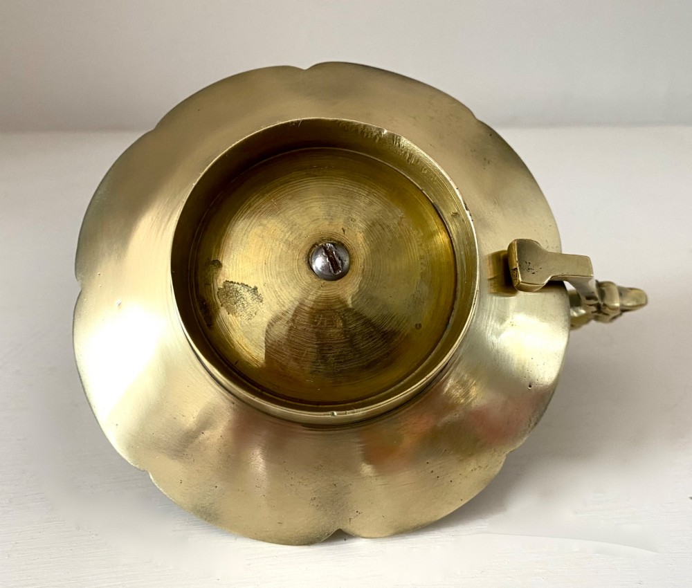 An antique French brass chamberstick featuring a scalloped tray base, turned candle socket, and a cast handle shaped like a grotesque face. View VII
