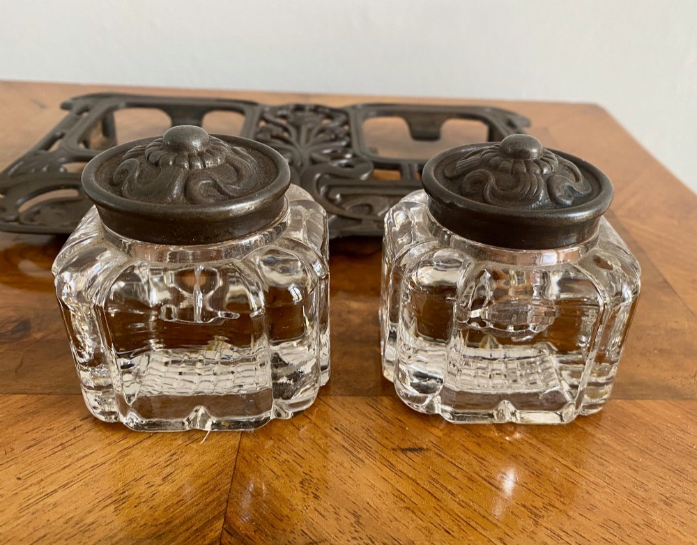 An Art Nouveau dark metal double inkstand featuring pierced floral scrollwork and two square glass inkwells with embossed metal lids. View VI