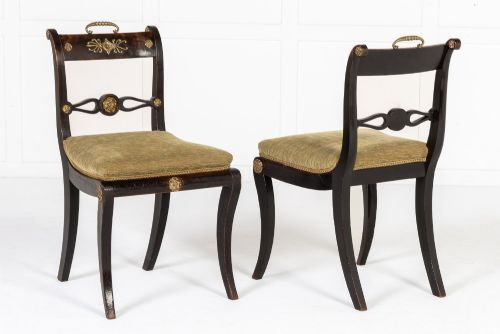 fig 1. A set of six early nineteenth-century Regency dining chairs crafted from dark wood with brass inlay detailing, brass top handles, and green upholstered seats.