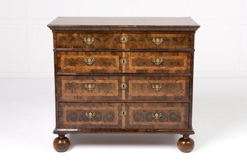 fig 1. A late 17th-century Dutch walnut chest of drawers featuring geometric oyster veneering, brass drop handles, keyhole escutcheons, and large turned bun feet.