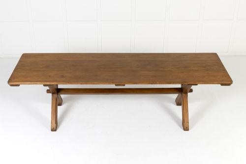 fig 1. An English pine refectory dining table featuring a rectangular plank top resting on an X-frame trestle base with a central stretcher.