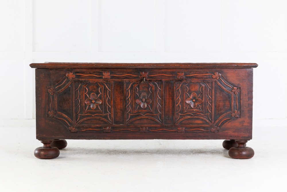 A 19th-century dark hardwood trunk featuring relief carvings of lions on the lid, carved floral front panels, and turned bun feet. View II
