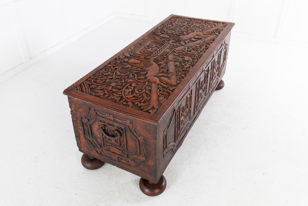 A 19th-century dark hardwood trunk featuring relief carvings of lions on the lid, carved floral front panels, and turned bun feet. View IV