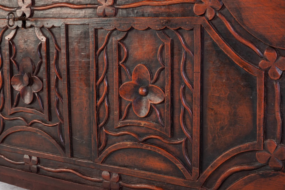 A 19th-century dark hardwood trunk featuring relief carvings of lions on the lid, carved floral front panels, and turned bun feet. View V