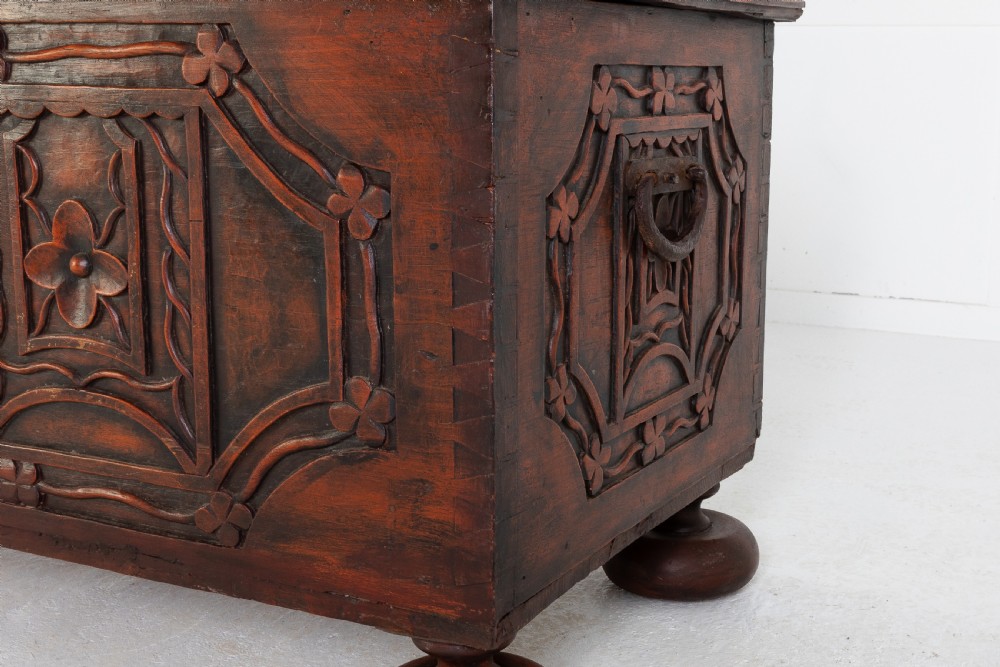 A 19th-century dark hardwood trunk featuring relief carvings of lions on the lid, carved floral front panels, and turned bun feet. View VI