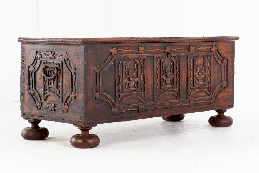 A 19th-century dark hardwood trunk featuring relief carvings of lions on the lid, carved floral front panels, and turned bun feet. View VII