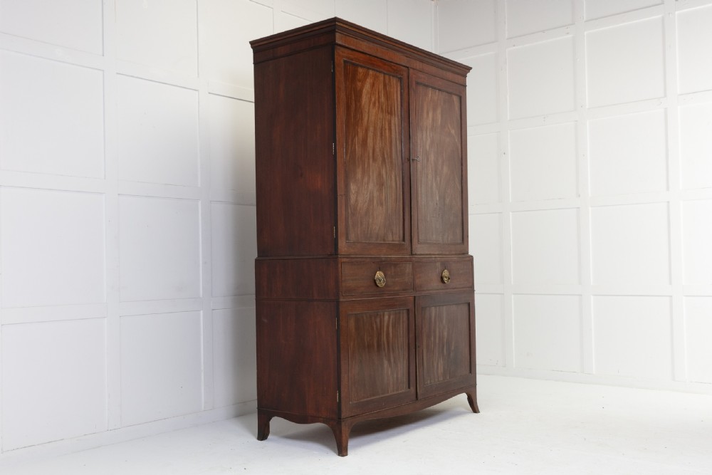 A George III mahogany linen press featuring flame mahogany panelled doors, brass handles, and splayed bracket feet. View II
