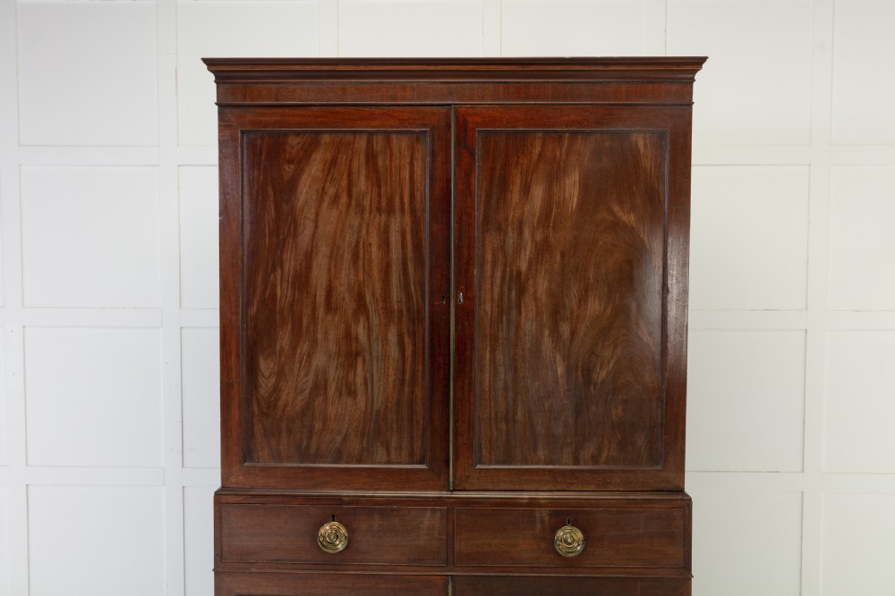 A George III mahogany linen press featuring flame mahogany panelled doors, brass handles, and splayed bracket feet. View III