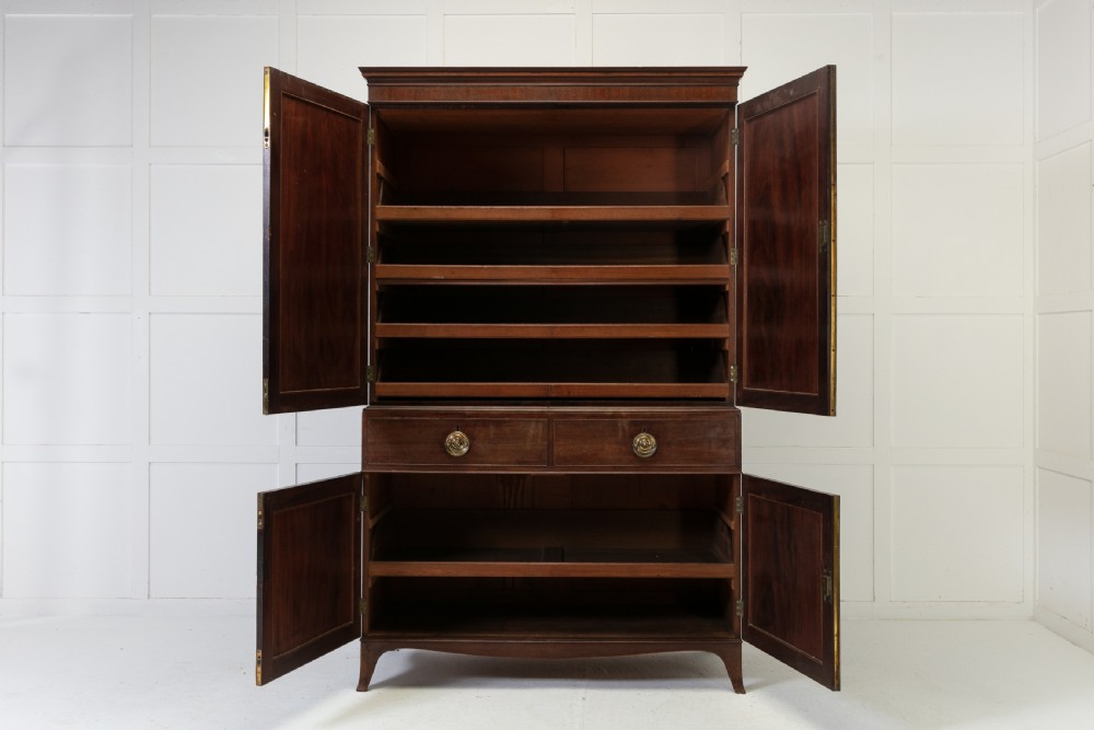 A George III mahogany linen press featuring flame mahogany panelled doors, brass handles, and splayed bracket feet. View VII