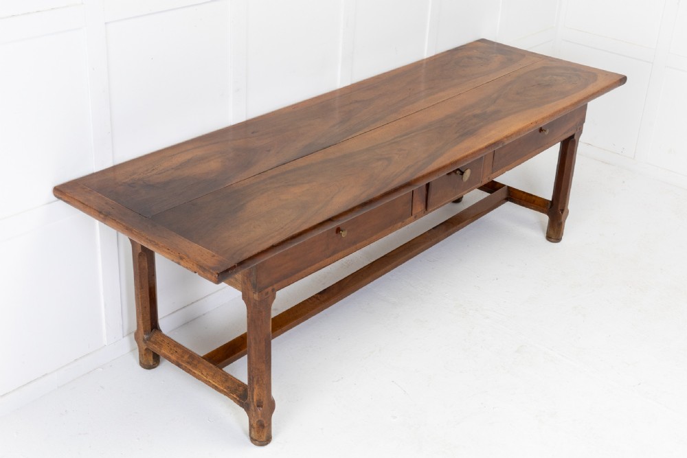 An elongated nineteenth-century French walnut serving table featuring a plank top, two front drawers with small brass knobs, and sturdy legs connected by a low stretcher base.