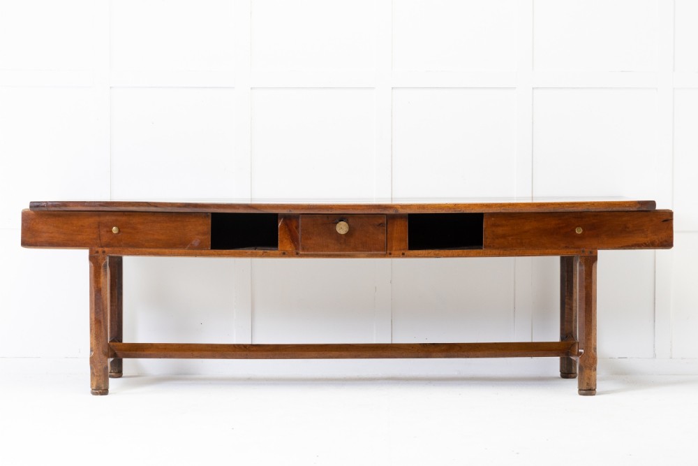 An elongated nineteenth-century French walnut serving table featuring a plank top, two front drawers with small brass knobs, and sturdy legs connected by a low stretcher base. View II