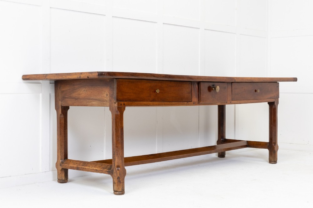 An elongated nineteenth-century French walnut serving table featuring a plank top, two front drawers with small brass knobs, and sturdy legs connected by a low stretcher base. View III