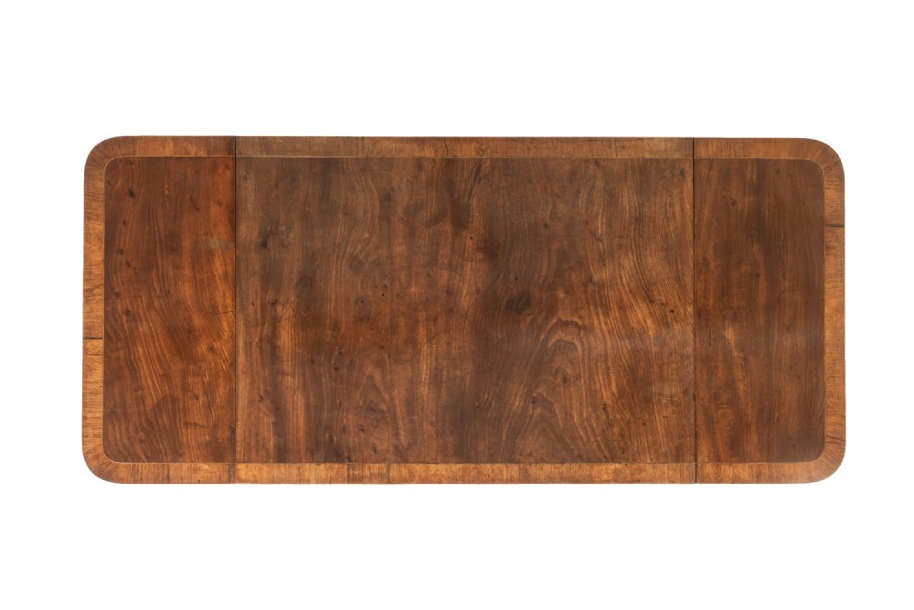A top-down view of a 19th-century English Regency mahogany sofa table featuring a rectangular surface with rounded corners, drop leaves, and crossbanded timber borders.