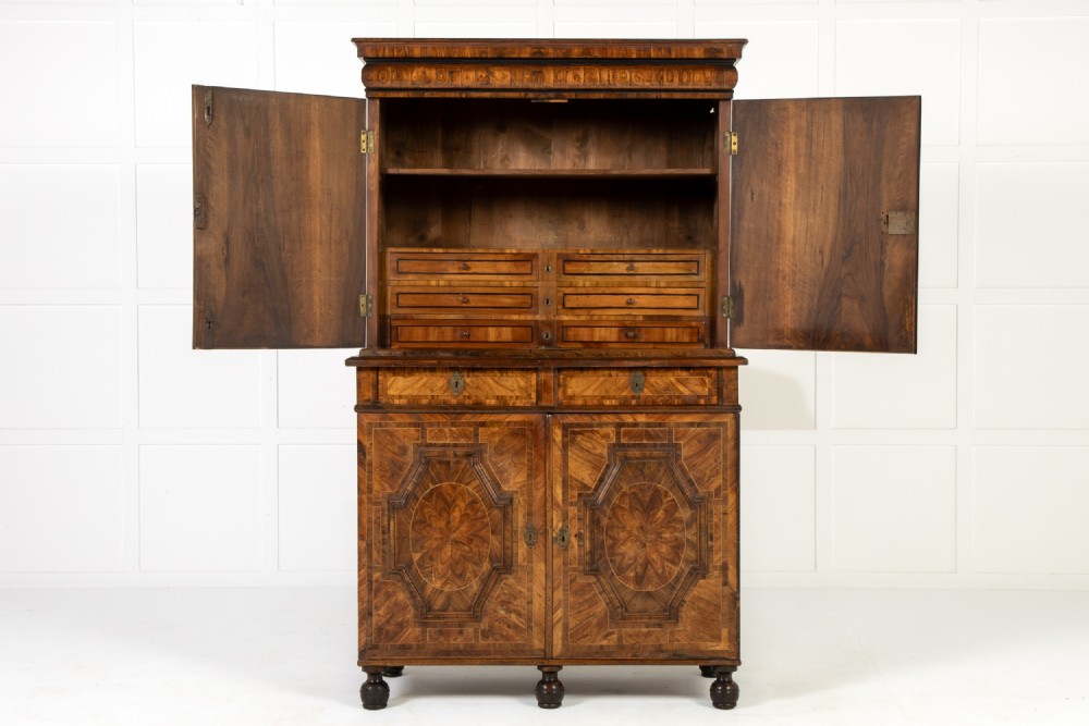 A two-tier seventeenth-century French walnut cabinet featuring geometric parquetry panels, central floral starburst inlays, two upper doors, two central drawers, two lower doors, and turned bun feet. View II