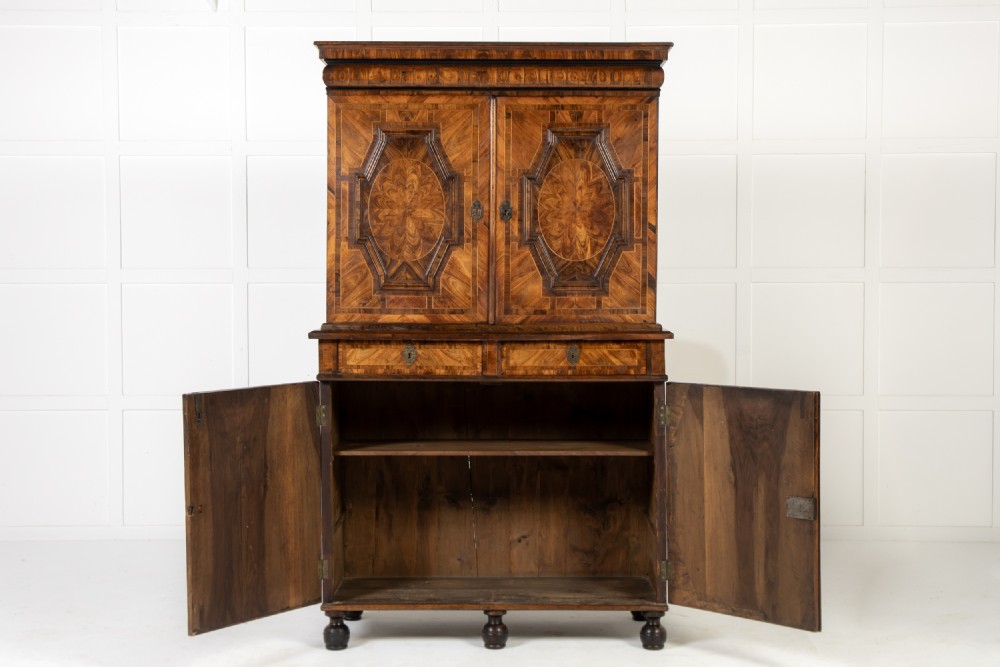 A two-tier seventeenth-century French walnut cabinet featuring geometric parquetry panels, central floral starburst inlays, two upper doors, two central drawers, two lower doors, and turned bun feet. View III