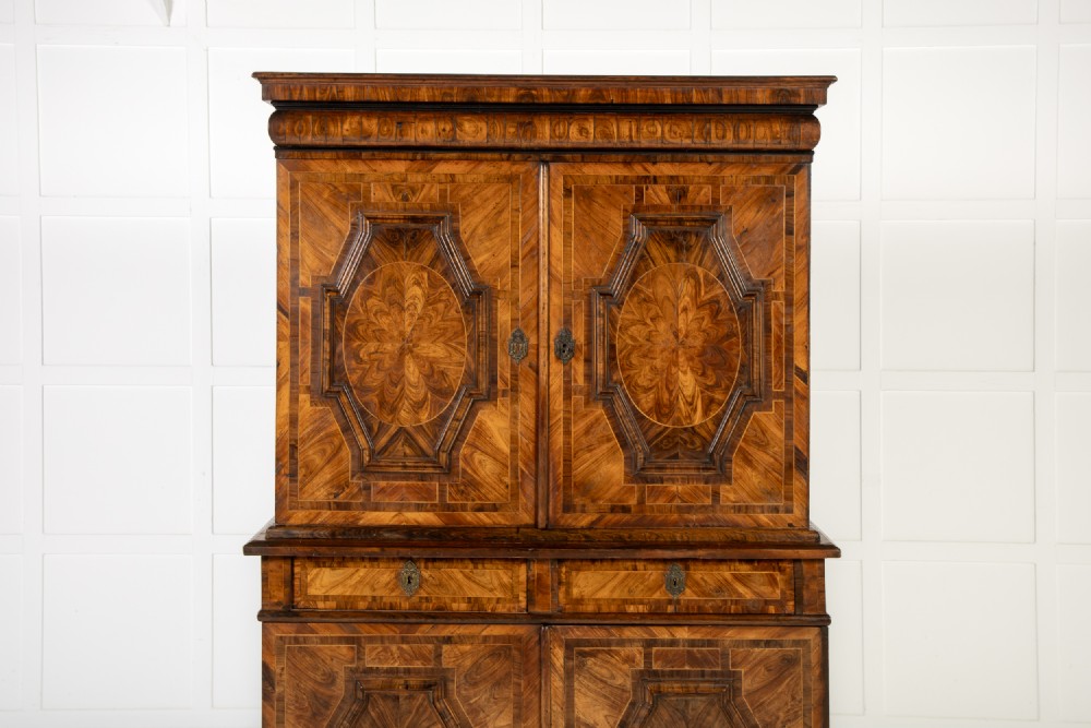 A two-tier seventeenth-century French walnut cabinet featuring geometric parquetry panels, central floral starburst inlays, two upper doors, two central drawers, two lower doors, and turned bun feet. View IV