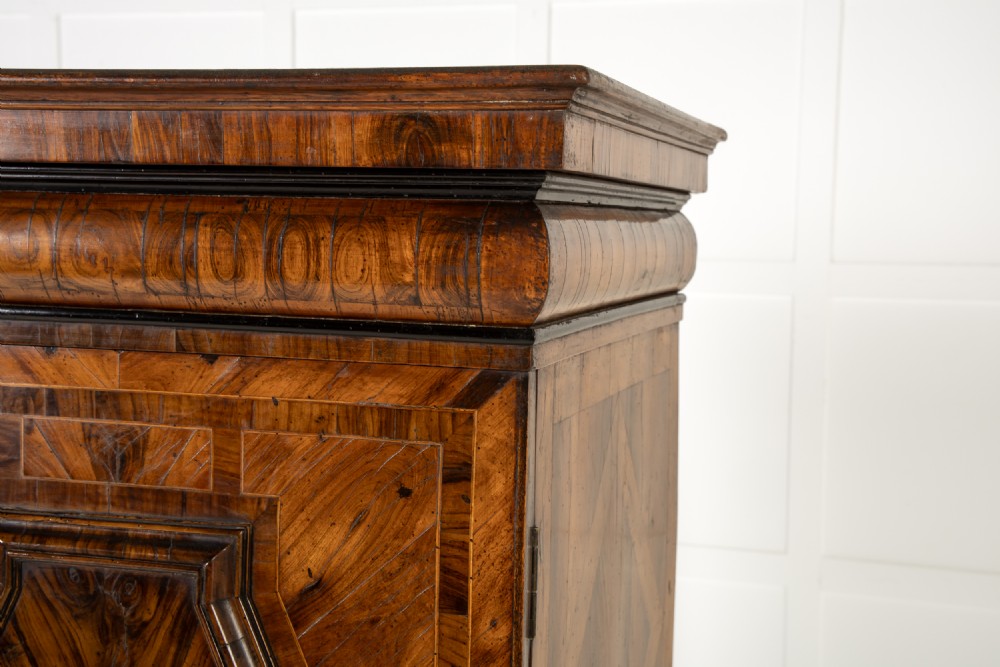A two-tier seventeenth-century French walnut cabinet featuring geometric parquetry panels, central floral starburst inlays, two upper doors, two central drawers, two lower doors, and turned bun feet. View VI