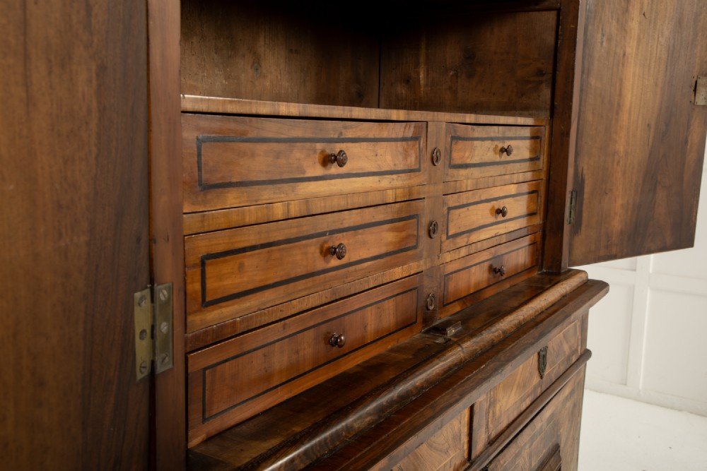 A two-tier seventeenth-century French walnut cabinet featuring geometric parquetry panels, central floral starburst inlays, two upper doors, two central drawers, two lower doors, and turned bun feet. View VII