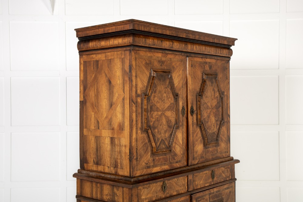 A two-tier seventeenth-century French walnut cabinet featuring geometric parquetry panels, central floral starburst inlays, two upper doors, two central drawers, two lower doors, and turned bun feet. View VIII