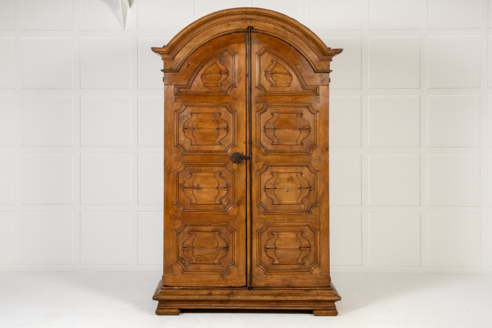 An eighteenth-century Italian pine armoire featuring an arched pediment, double doors with raised moulded panels, and wrought iron lock hardware. View III