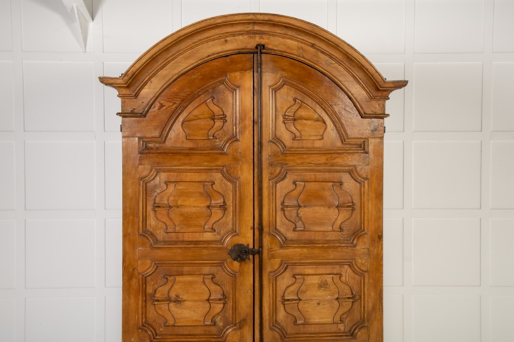 An eighteenth-century Italian pine armoire featuring an arched pediment, double doors with raised moulded panels, and wrought iron lock hardware. View IV