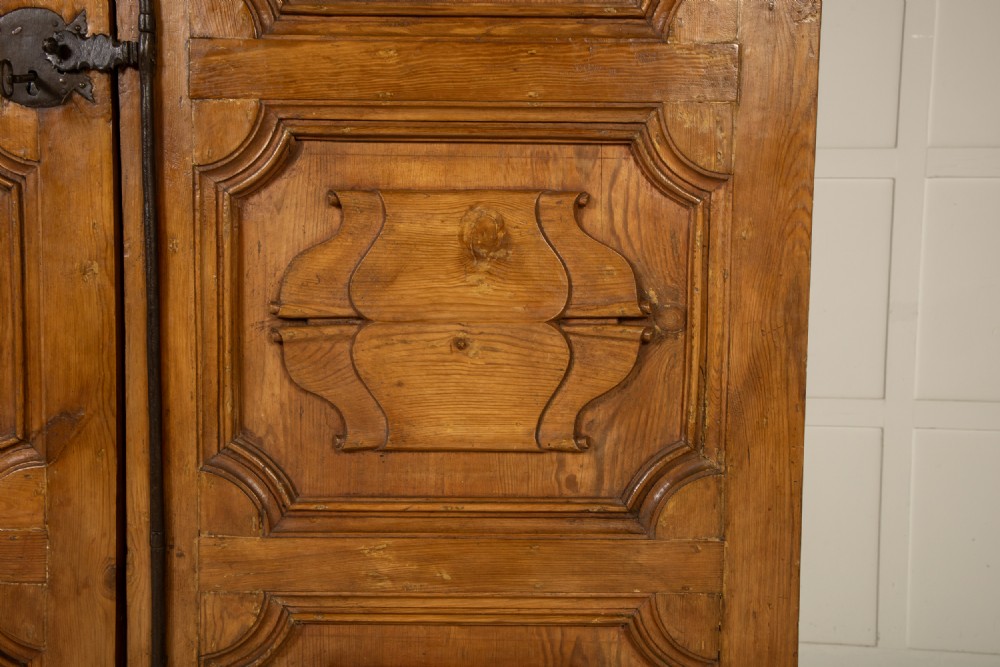 An eighteenth-century Italian pine armoire featuring an arched pediment, double doors with raised moulded panels, and wrought iron lock hardware. View V