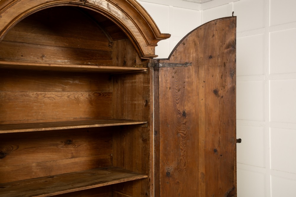 An eighteenth-century Italian pine armoire featuring an arched pediment, double doors with raised moulded panels, and wrought iron lock hardware. View VII