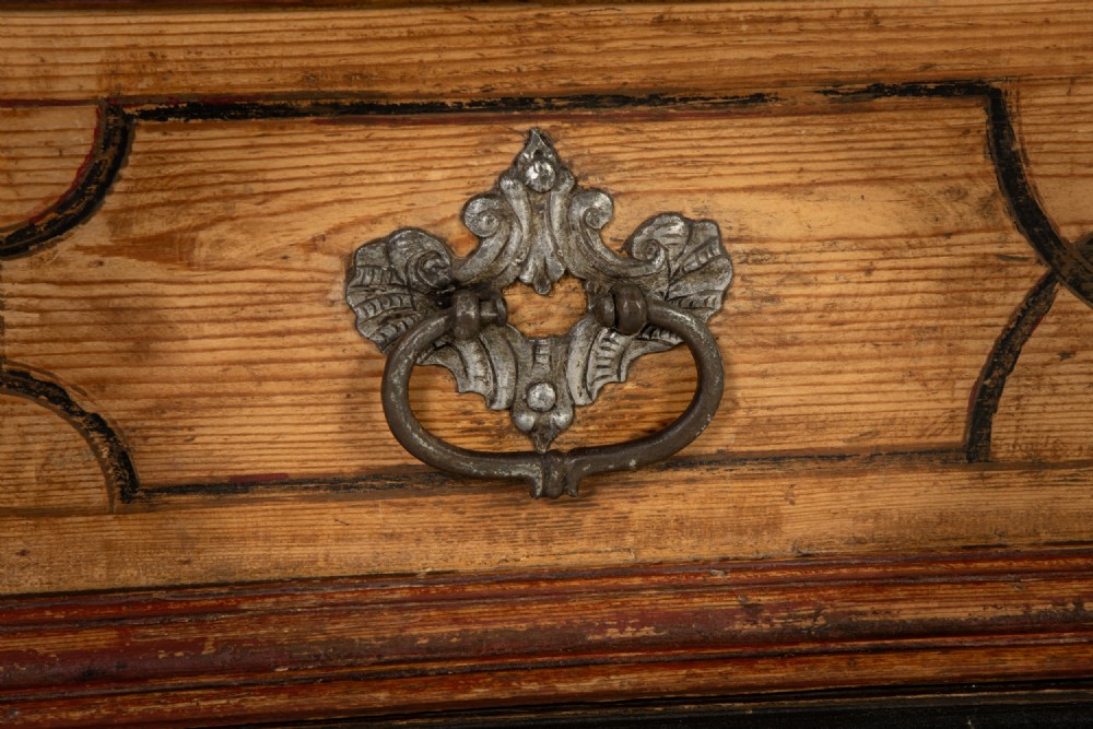 An 18th-century two-part pine cabinet featuring an arched upper cupboard section decorated with black painted geometric scrollwork over a base with three wide drawers. View VII