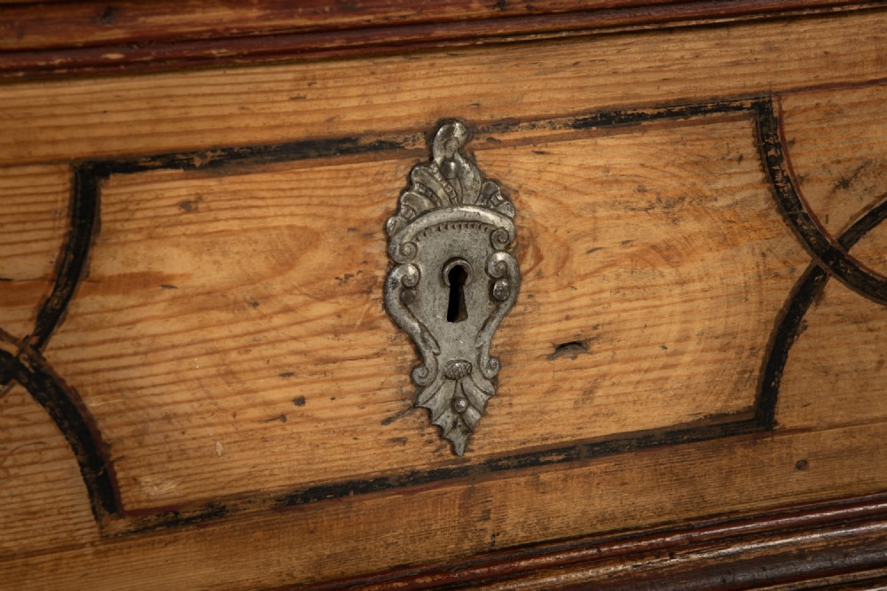 An 18th-century two-part pine cabinet featuring an arched upper cupboard section decorated with black painted geometric scrollwork over a base with three wide drawers. View VIII