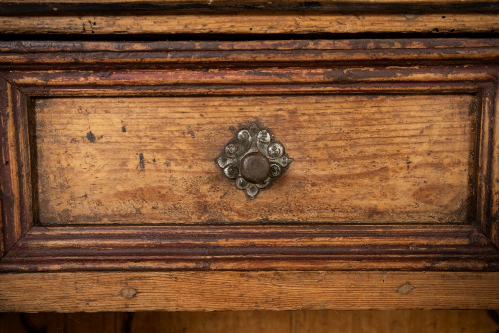 An 18th-century two-part pine cabinet featuring an arched upper cupboard section decorated with black painted geometric scrollwork over a base with three wide drawers. View IX