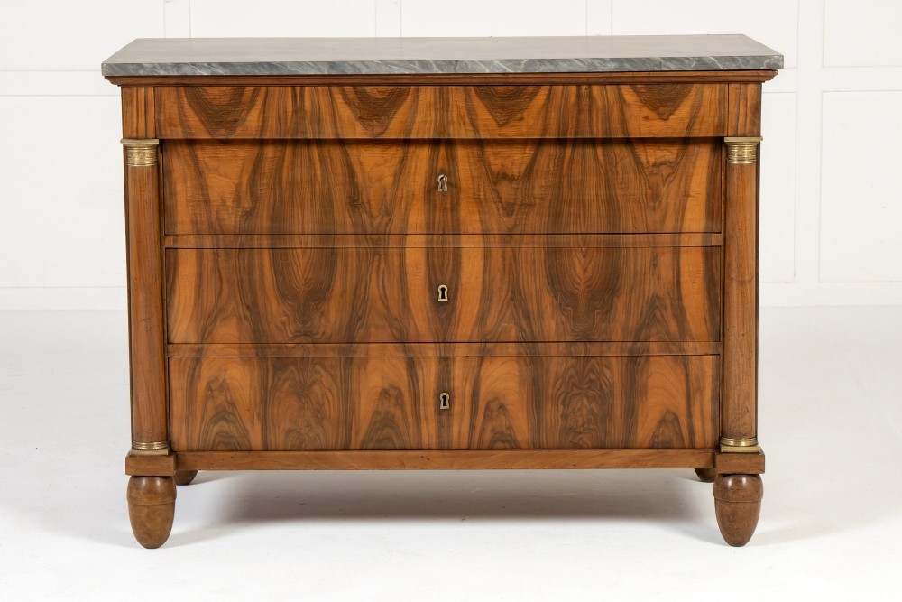 A 19th-century Italian walnut commode featuring a grey marble top, three drawer fronts with bookmatched grain, flanking column pilasters with brass mounts, and turned feet. View II
